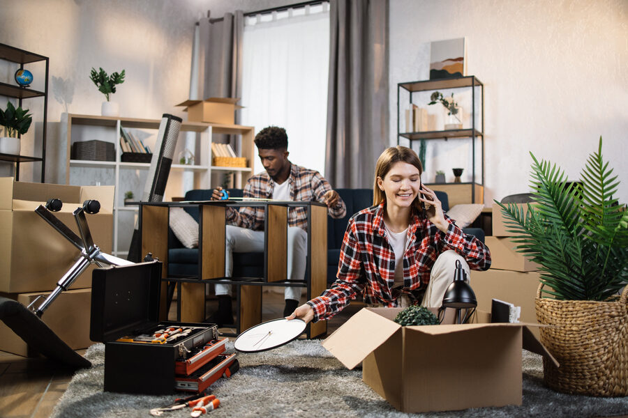 Woman talking on mobile while man assembling furniture